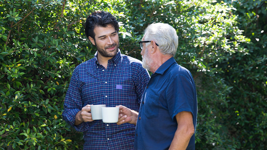 Elderly man and son having a talking over a cup of coffee.