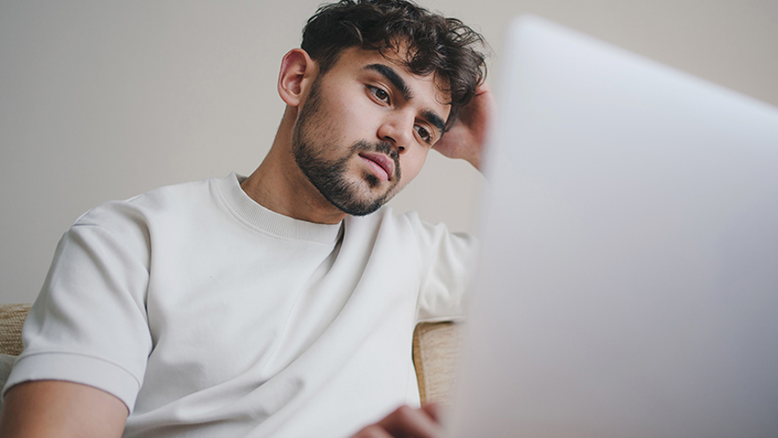 Young man staring listlessly at a computer screen