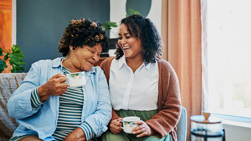 Mother and daughter having coffee and laughing
